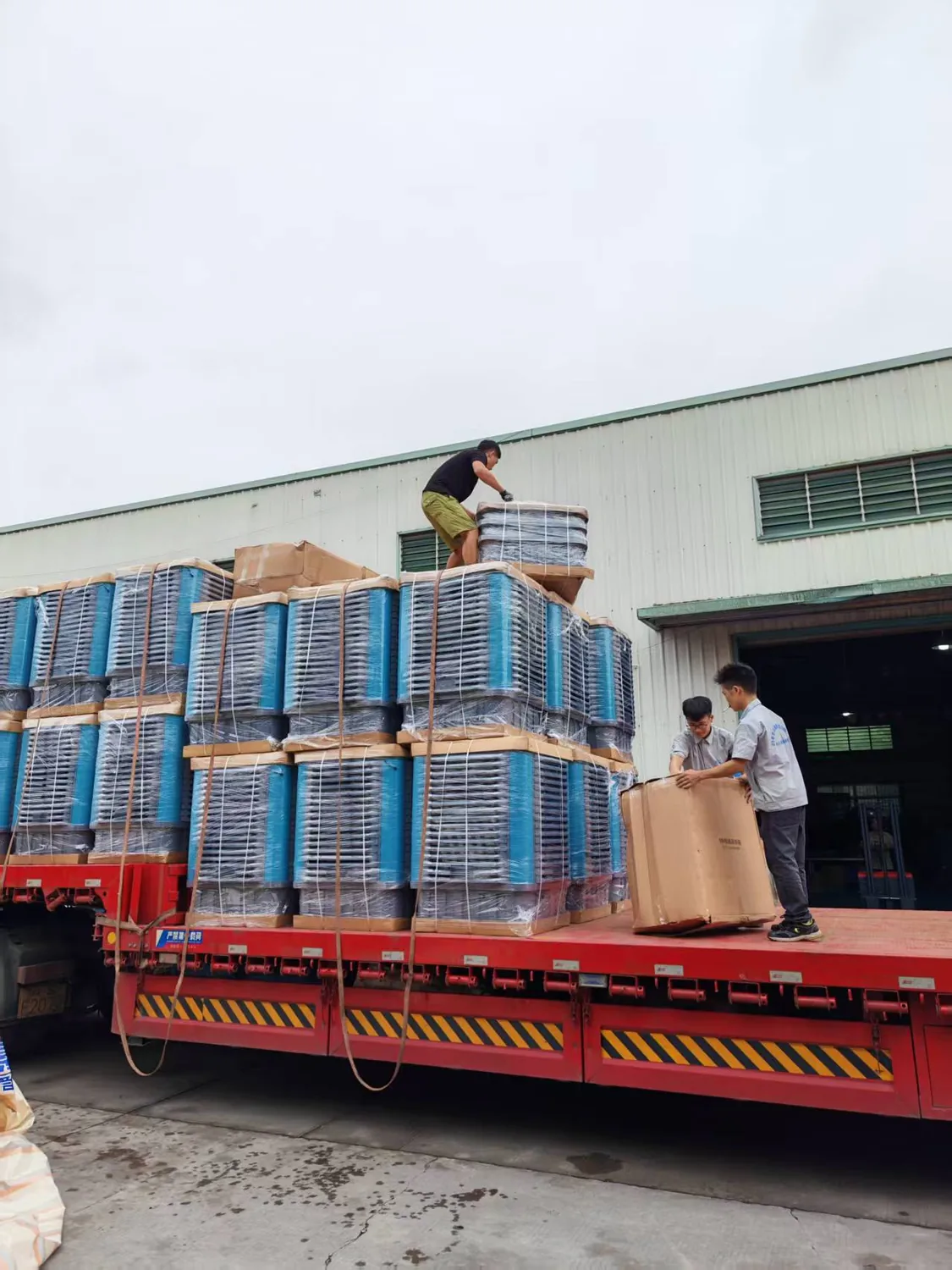 Workers securing packaged evaporative coolers on delivery truck